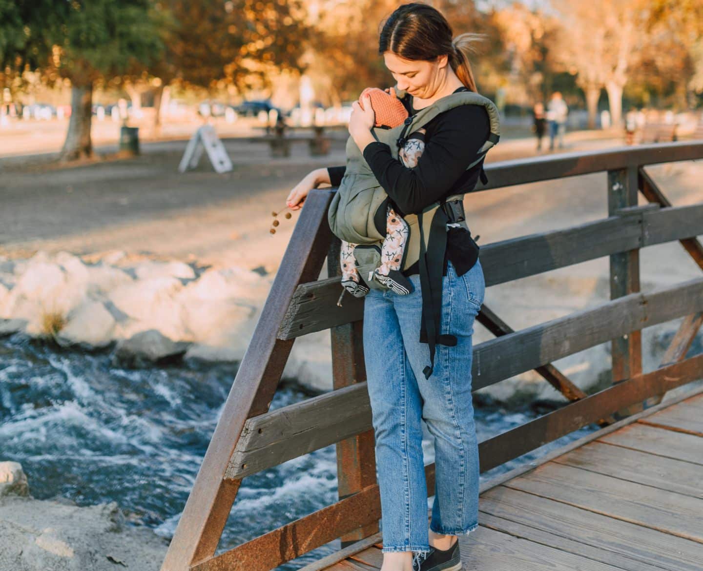 woman standing on wooden bridge with her baby