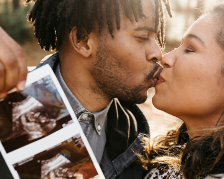 couple kissing while holding up an ultrasound