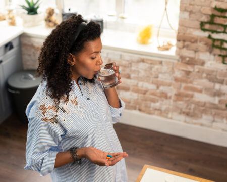 Pregnant lady taking prenatal vitamins with water