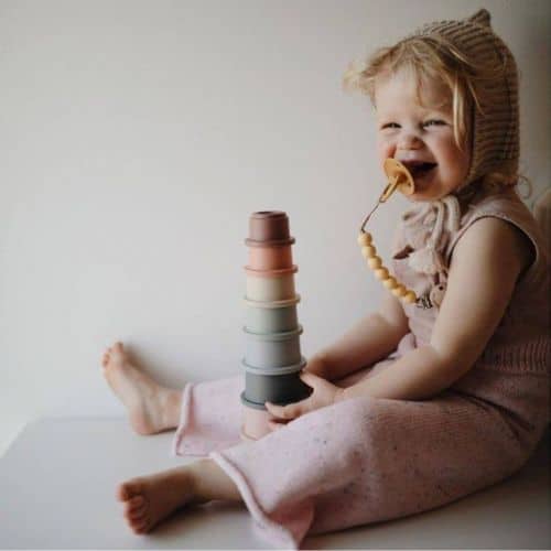 little girl playing with mushie cups