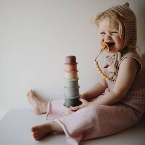 little girl playing with mushie cups