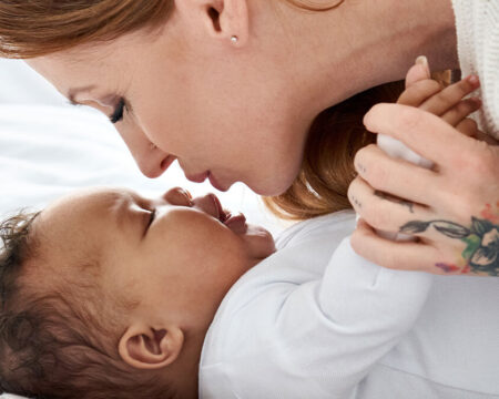 mom with tattoos giving newborn a kiss