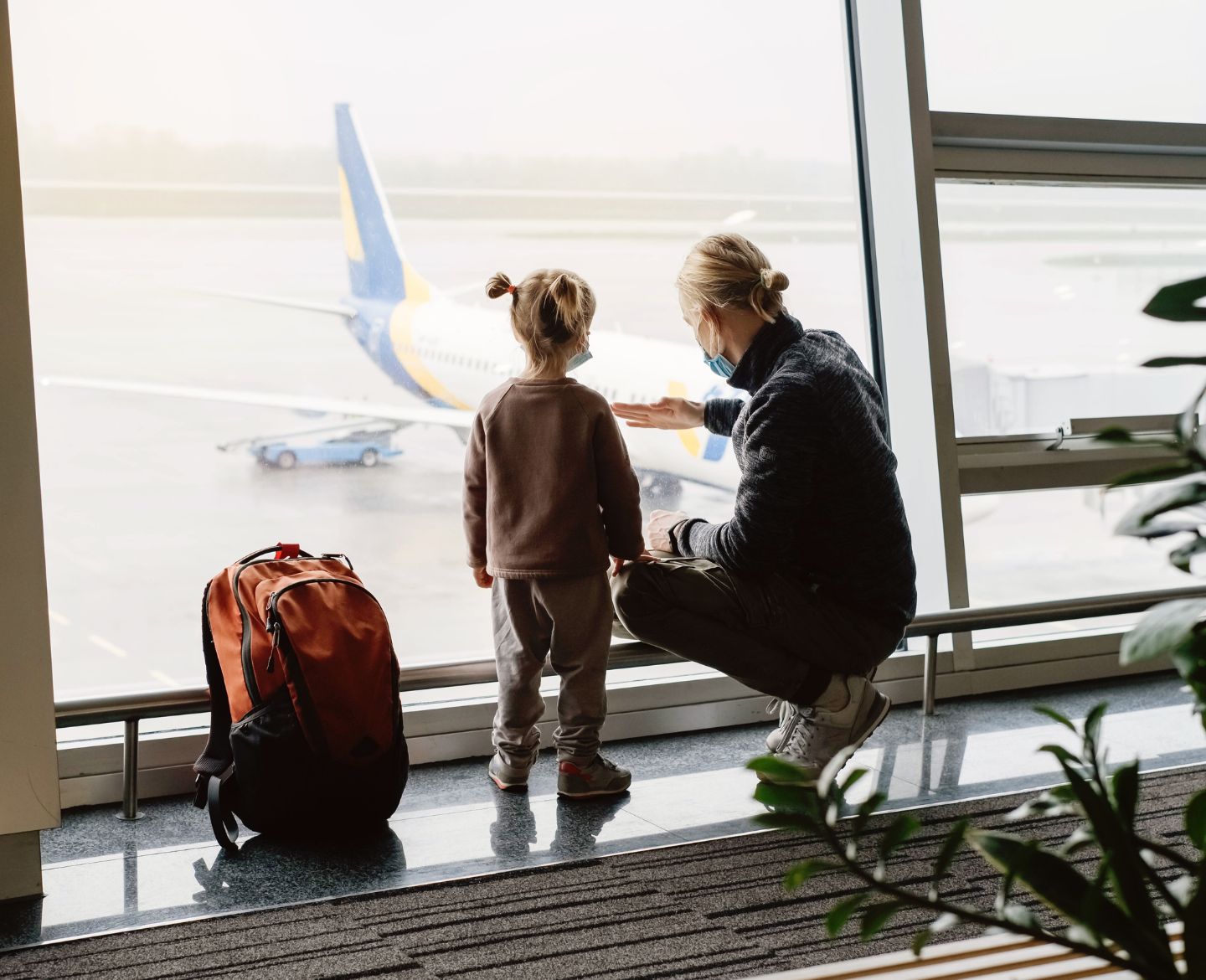 Mother with child in airport looking at airplane