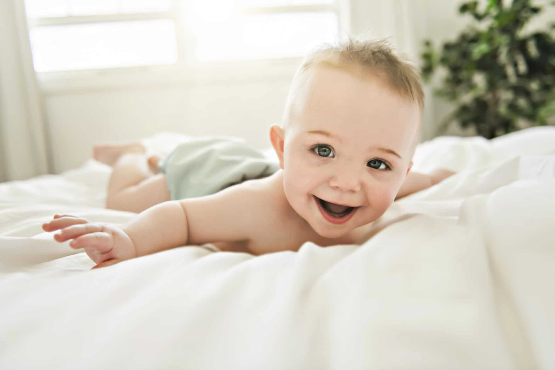 baby wearing a cloth diaper laying on a bed