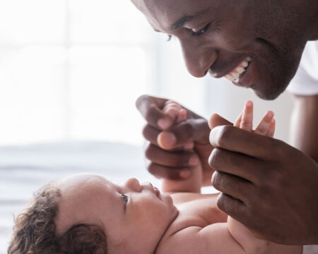 smiling father playing with his baby normalize paternity leave