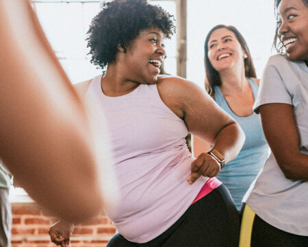 two women laughing together during a dance class