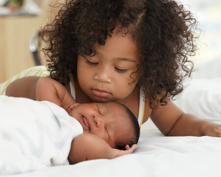 young girl looking over her baby sister