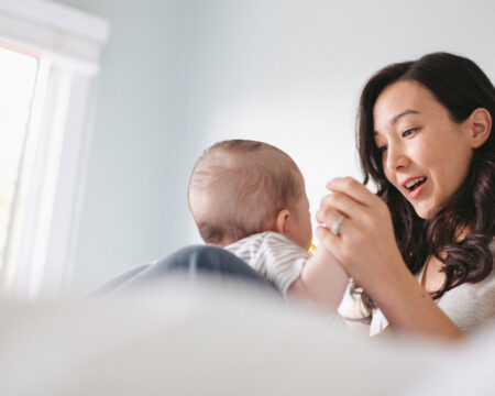 young mom playing with baby on the bed